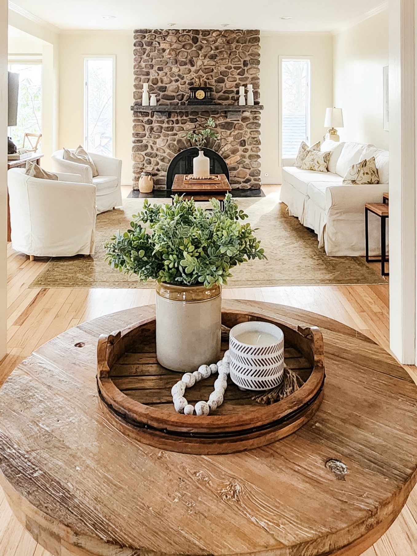 Styled entry table with a tray, candle, plant and beaded garland with living room in the background